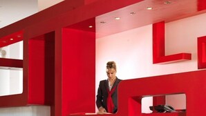 A modern interior with red accents and a unique, curved red chair. - Airotel Patras Smart (Patras)