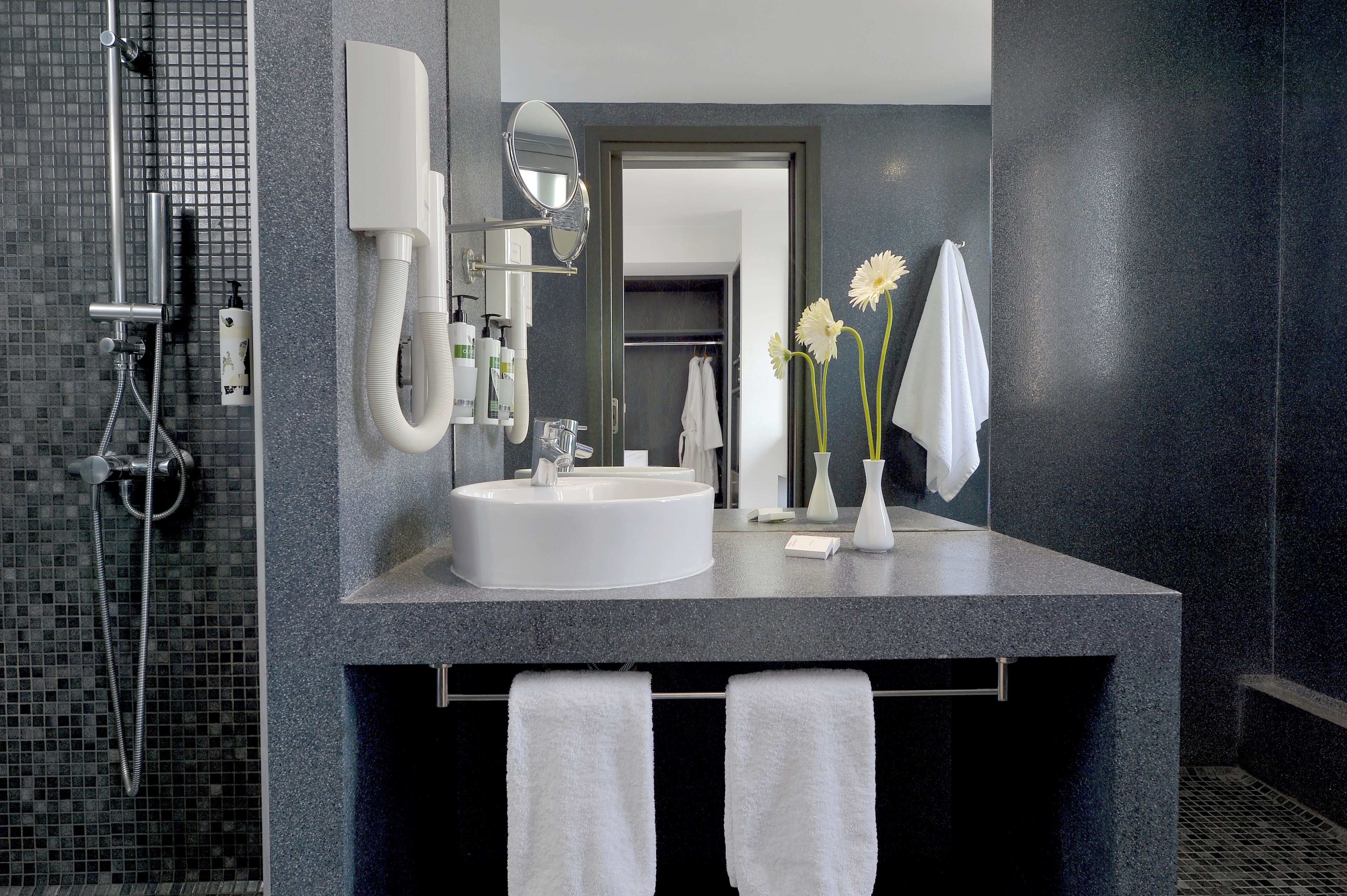Un baño moderno con un espejo grande, un lavamanos y una zona de ducha.