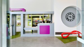 Una zona de recepción moderna con un reloj grande, una barra de atención y un separador de vidrio.