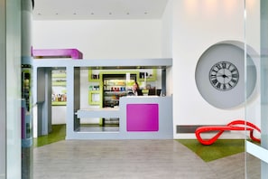Una zona de recepción moderna con un reloj grande, una barra de atención y un separador de vidrio.