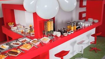 A buffet setup with a red and white color scheme, featuring a variety of food items and a central serving area.