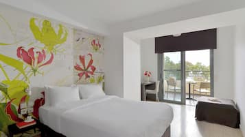 A hotel room with a large bed, a desk with a chair, and a balcony with a table and chairs.