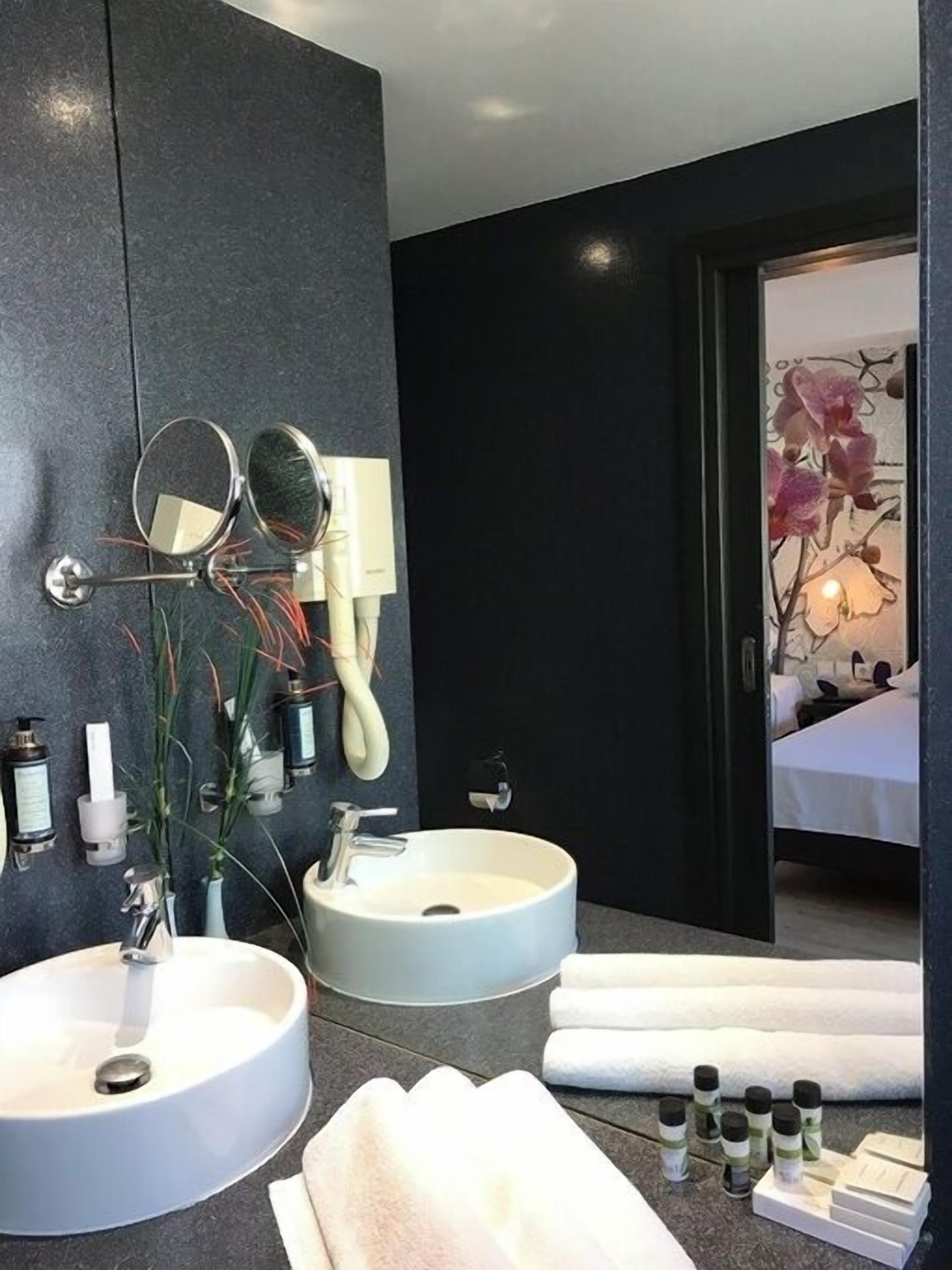 A modern bathroom with two sinks, a hairdryer, and a mirror.