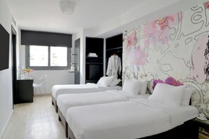Habitación de hotel con dos camas, un escritorio, una silla, un armario y un amplio mural floral.