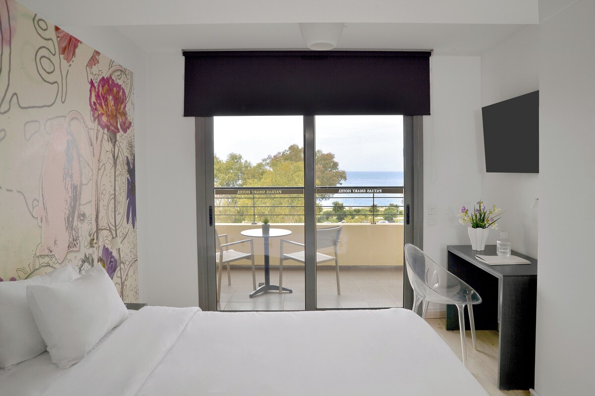 Una habitación de hotel con cama, escritorio y balcón con vistas al mar.