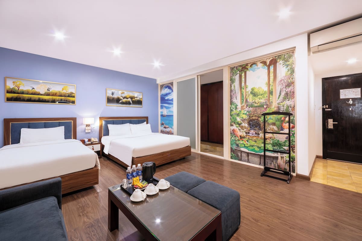 A hotel room with two beds, a coffee table with amenities, and a view of a garden through a sliding door.