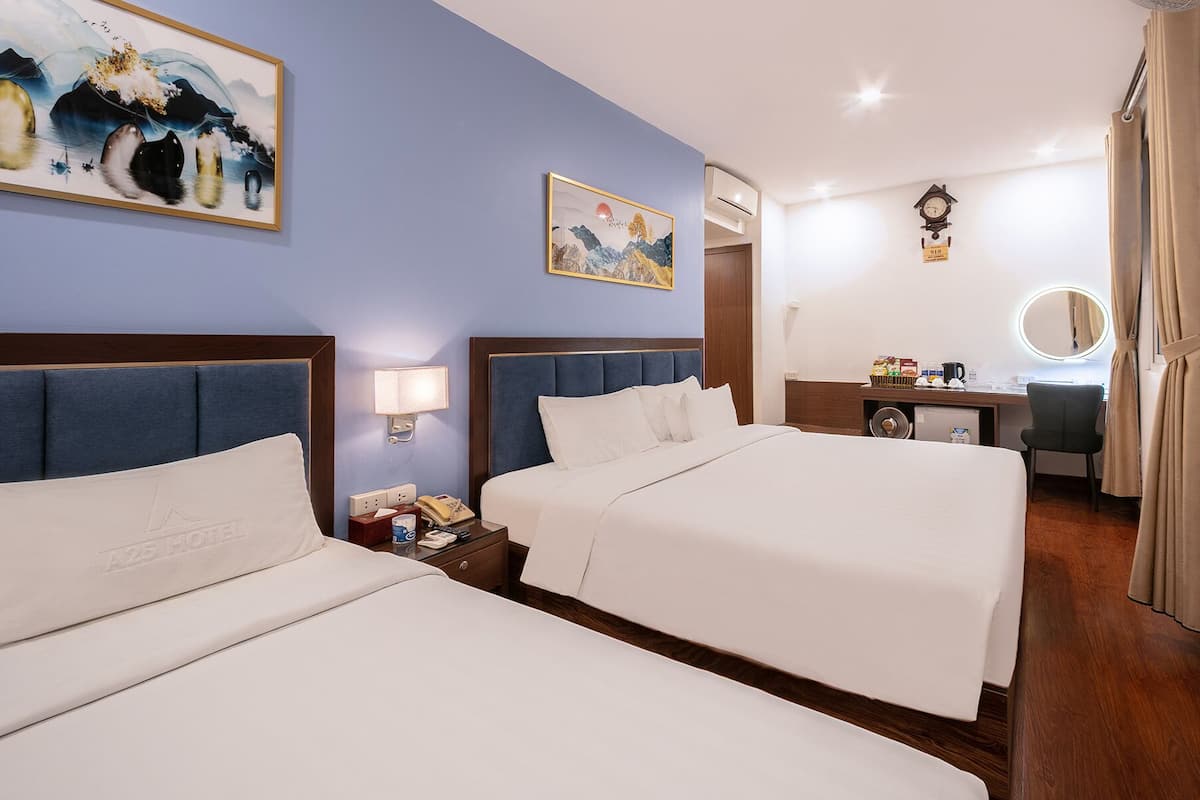 A hotel room with two beds, a desk, a mirror, and a clock on the wall.