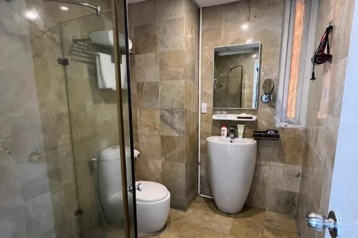 A bathroom with a glass shower enclosure, a toilet, a sink, and a mirror.