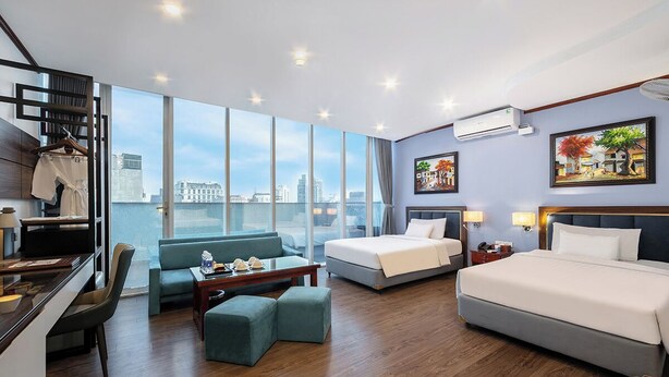 Ein Hotelzimmer mit großem Fenster, einer Couch, einem Bett, einem Schreibtisch und einem Sessel.