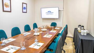 A conference room with a long table, chairs, and a screen displaying a logo.