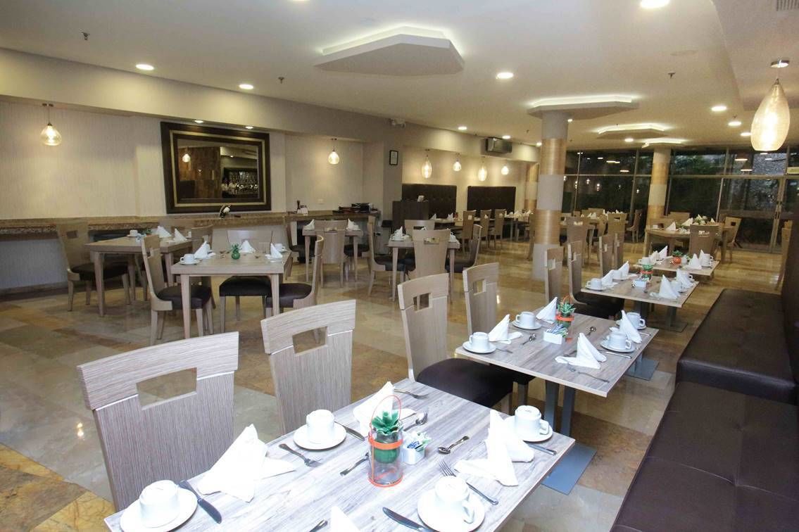 A spacious dining area with multiple tables and chairs, well-lit with ceiling lights, and a large mirror on the wall.