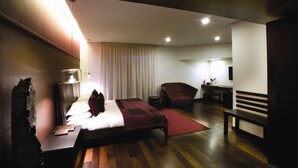 A modern hotel room with a bed, bedside table, lamp, chair, and a small desk with a chair. - The Park Pod (Chennai)