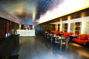 A modern restaurant with a bar area, seating with tables and chairs, and a stone wall with framed pictures. - The Park Pod (Chennai)