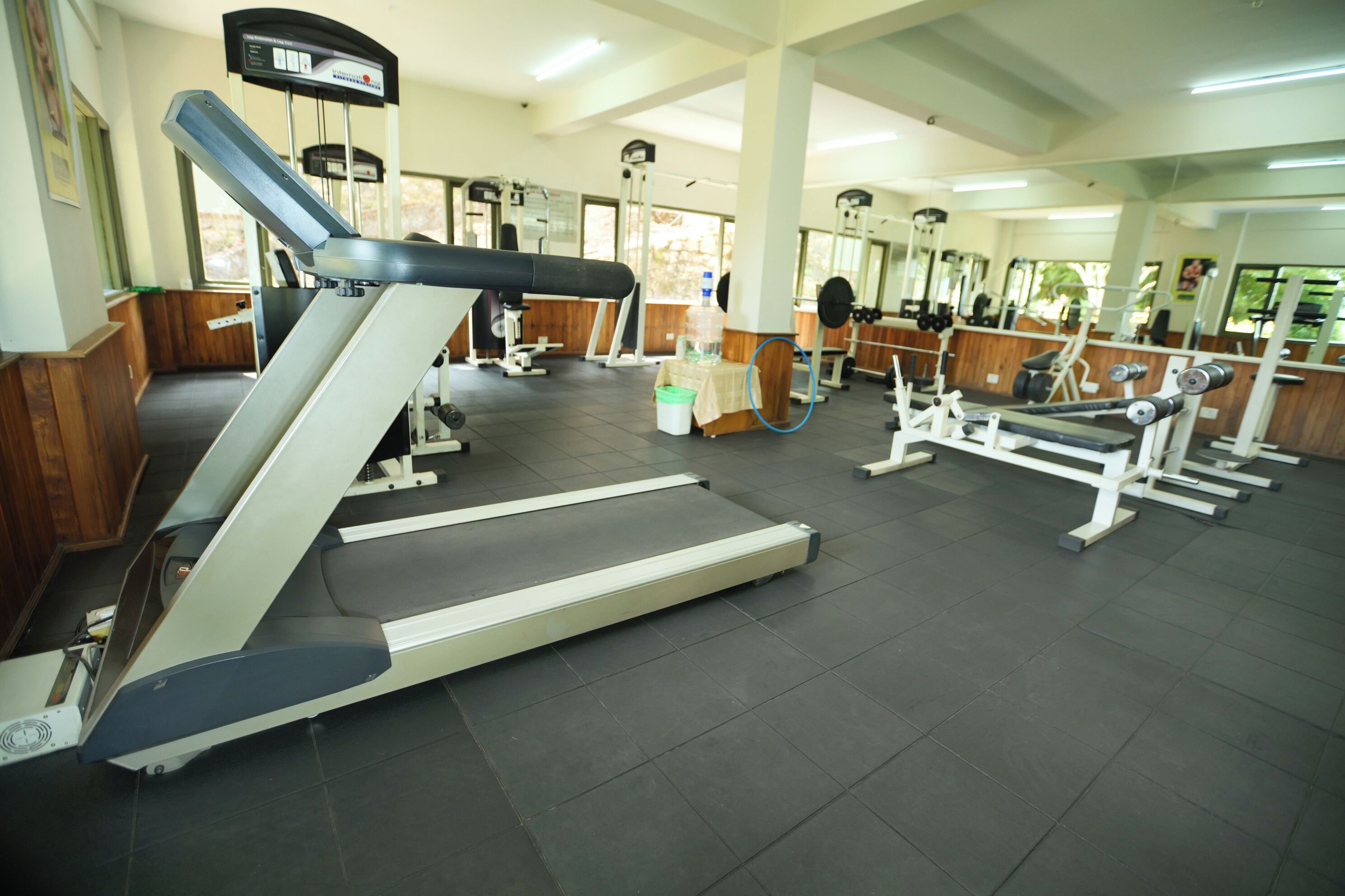 Un gimnasio con cintas de correr, máquinas de pesas y un espejo grande.