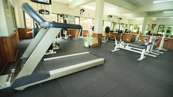 Un gimnasio con cintas de correr, máquinas de pesas y un espejo grande.