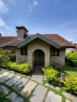 A stone house with a tiled roof, a stone chimney, and a front door with a small porch.