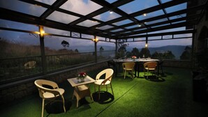 An outdoor patio with a table and chairs, a view of the landscape, and a pergola structure.