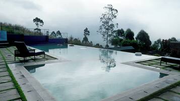 Una piscina al aire libre, sombrillas, sillones reclinables de piscina