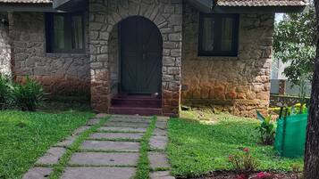 A stone house with a tiled roof, a stone archway entrance, and a paved pathway leading to the door.