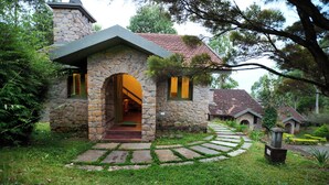 A stone house with a stone archway entrance, a red-tiled roof, and a stone pathway leading to the door.