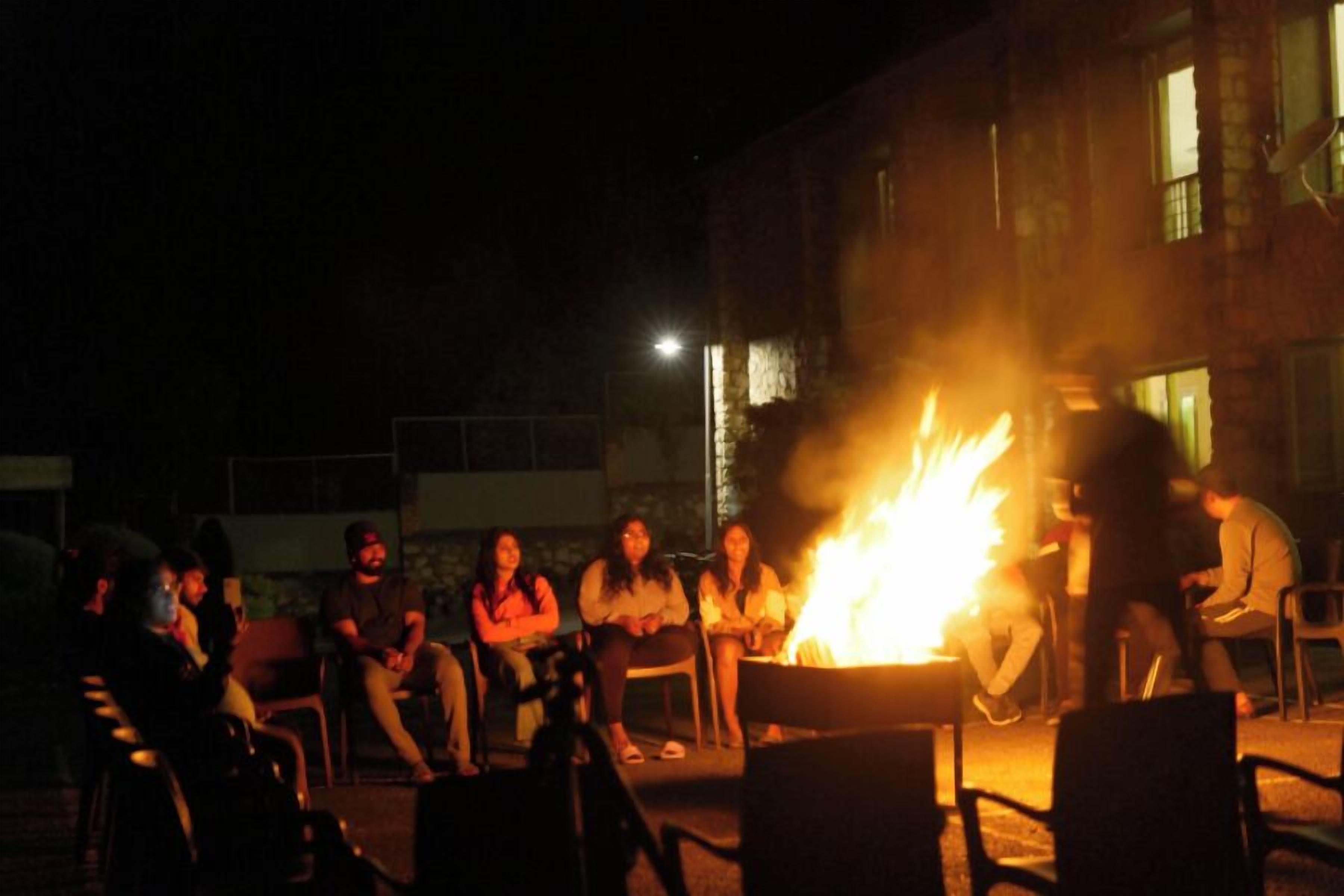 Un grupo de personas reunidas alrededor de una fogata por la noche.