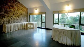 Relax in a spacious room with a high ceiling, featuring a large round table and comfortable seating areas.