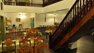 Un comedor con varias mesas y sillas, una escalera y una barra de buffet.