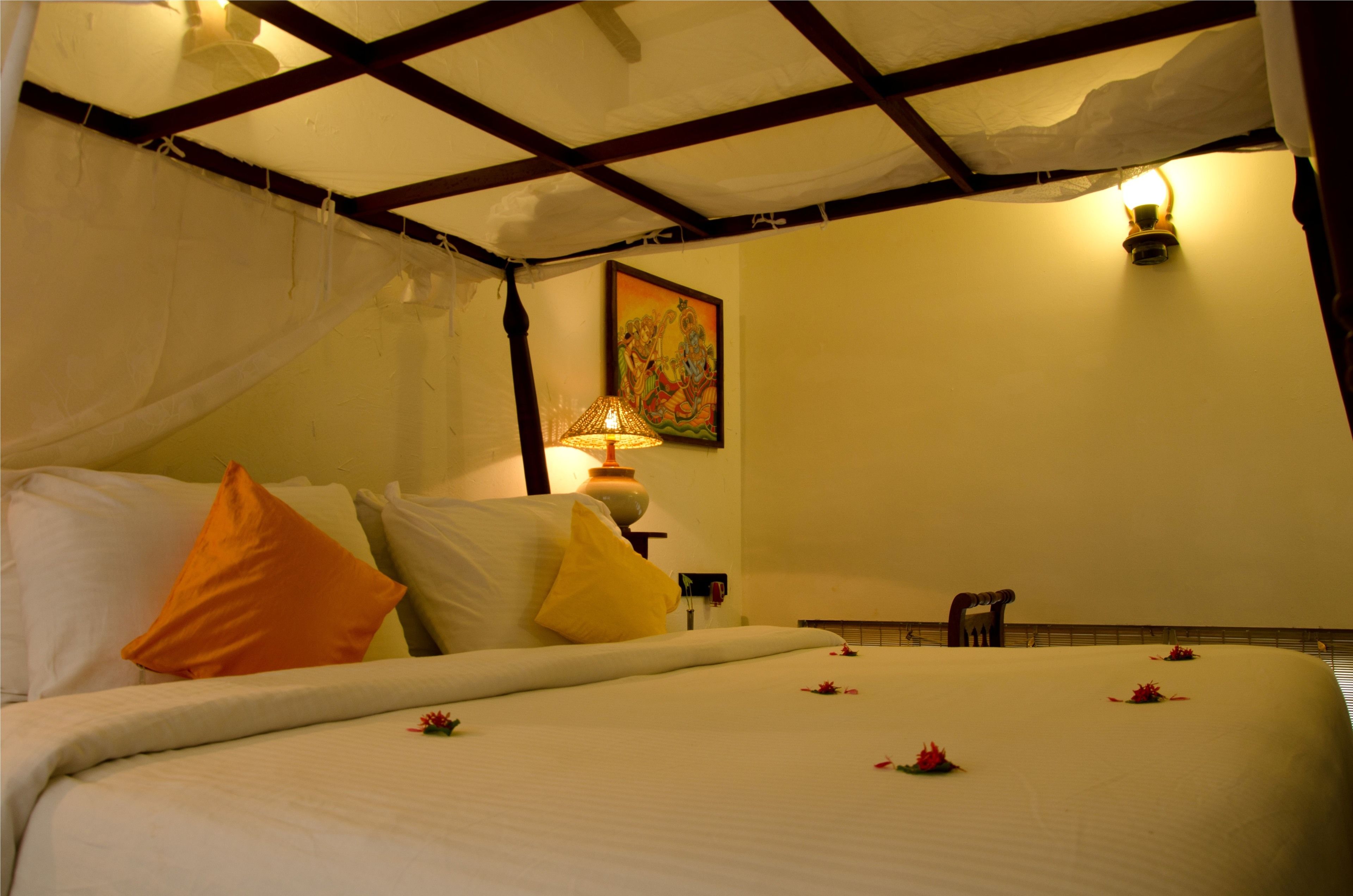 A hotel room with a bed, a nightstand, a lamp, and a painting on the wall.