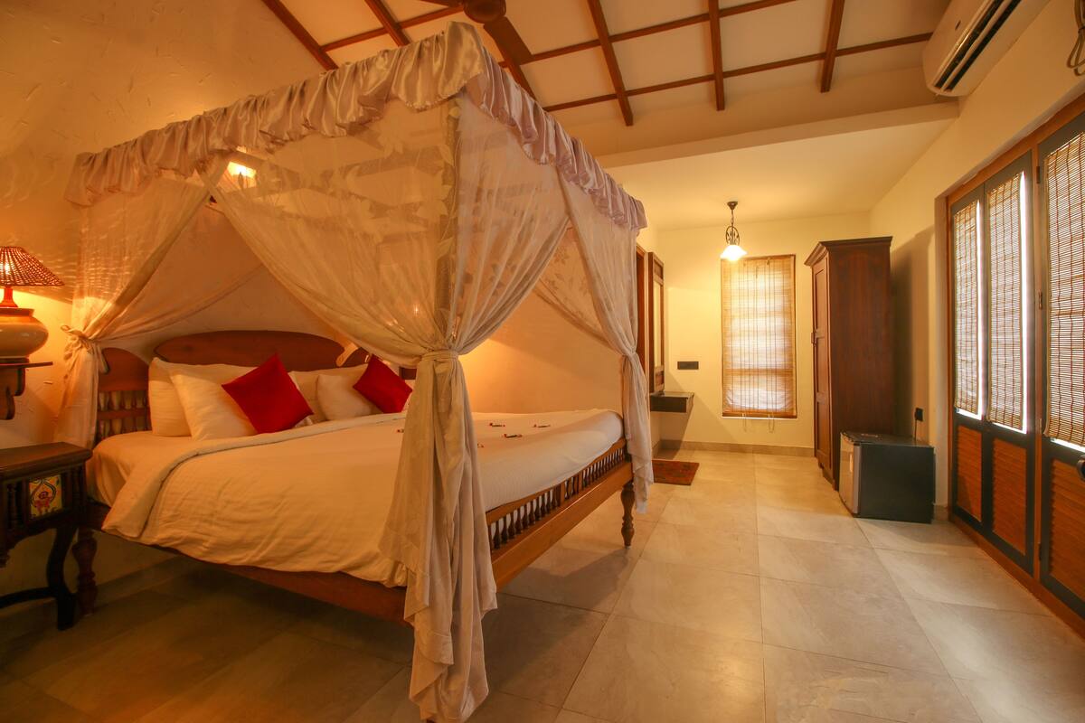 A bedroom with a four-poster bed, a nightstand, and a bedside table with a lamp.