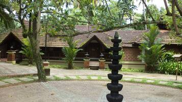 A traditional building with a tiled roof, surrounded by lush greenery and a stone pathway.