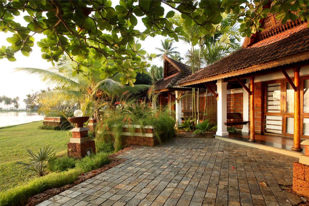 A traditional building with a tiled roof, a brick pathway, and lush greenery.