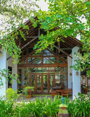 A wooden structure with large glass windows and a covered patio area with furniture. - Punnamada Resorts (Ambalapuzha)