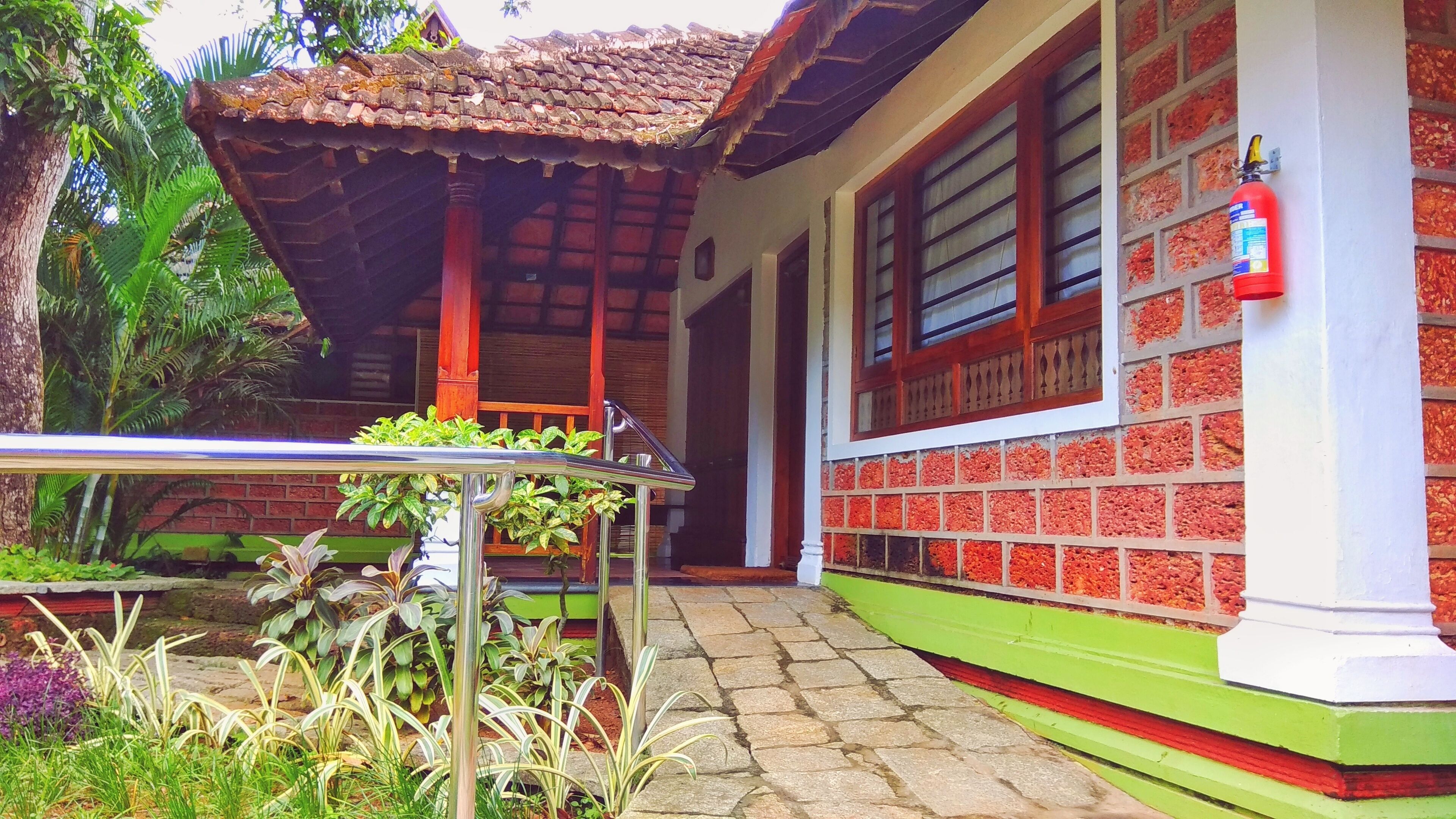 A traditional house with a tiled roof, a balcony with plants, and a brick wall.