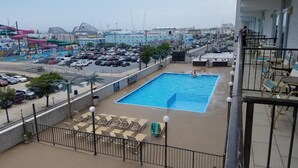 Una piscina amb gandules i vista a un pàrquing i edificis al fons.