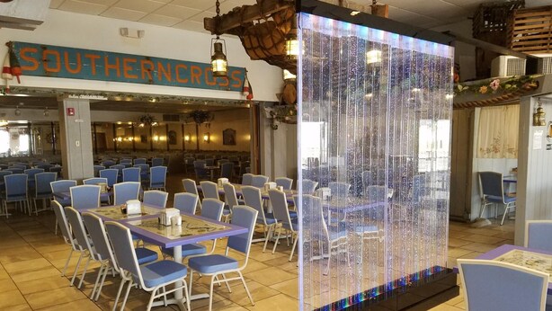Un restaurant amb caires i taules blaves, una instal·lació de llums decoratives i un cartell amb la frase "SOUTHERN CROSS".