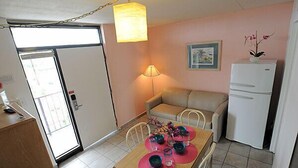 Un espai habitable reduït amb zona de menjador, petita cuina i una porta que dóna a un balcó.