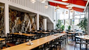 A modern restaurant with high ceilings, exposed brick walls, and multiple dining areas with tables and chairs. - Hotell Mörby AB, Patienthotell (Danderyd)