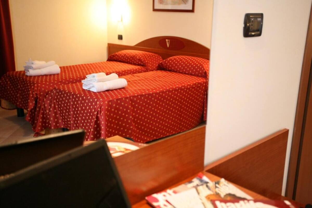 A hotel room with two beds, each with red bedding and white towels.