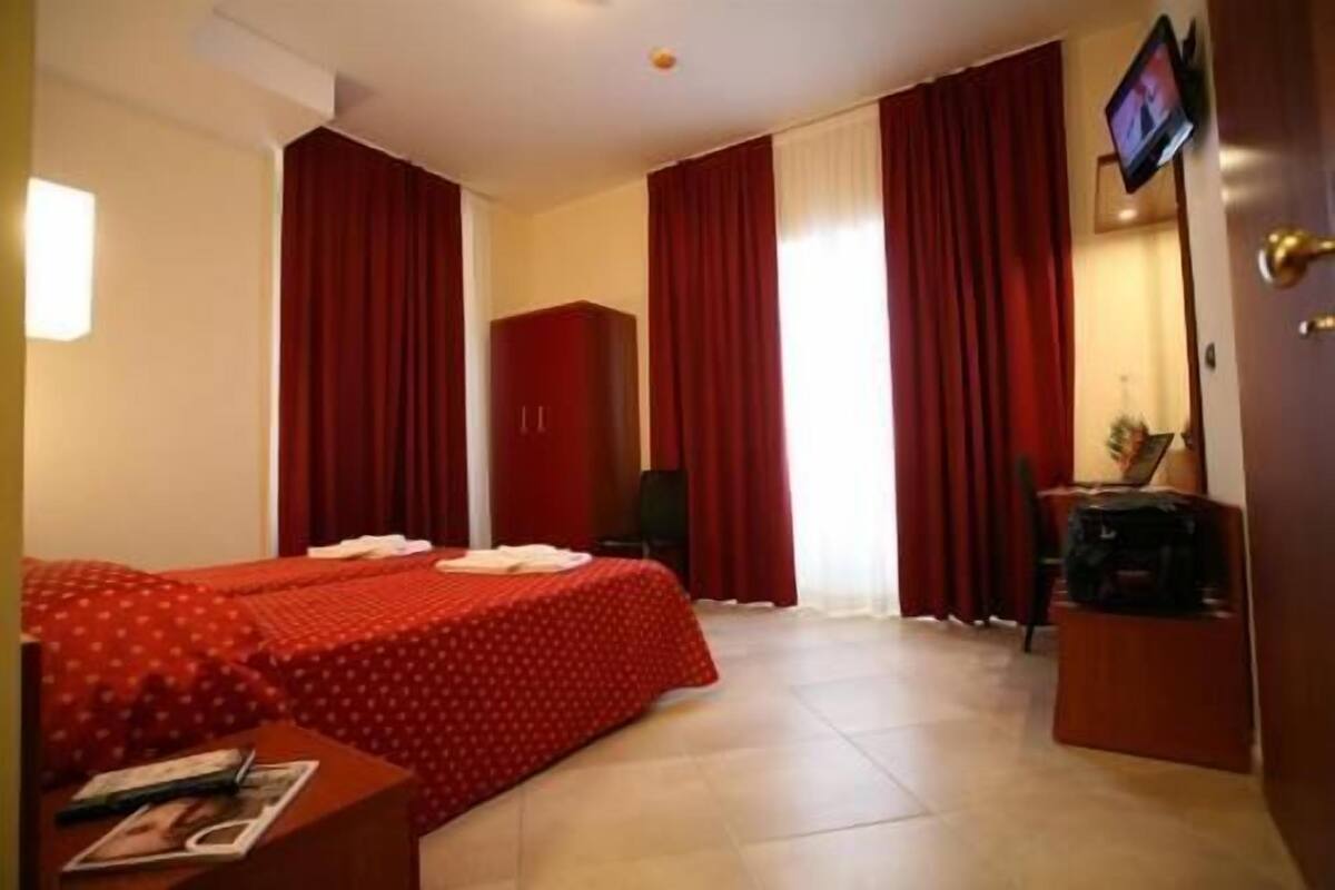 A hotel room with a bed, a desk, a chair, and a TV.