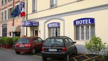 Un hotel con dos coches aparcados delante, una bandera europea y un cartel que indica una categoría de 3 estrellas.