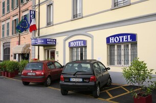 Un hotel con dos coches aparcados delante, una bandera europea y un cartel que indica una categoría de 3 estrellas.