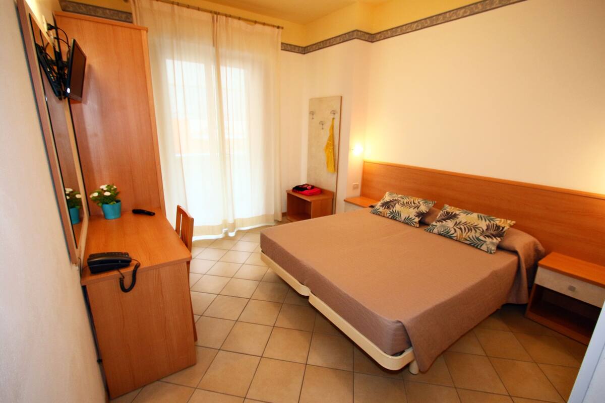 Une chambre d’hôtel comprenant un lit, un bureau avec une chaise, une petite table et une table de chevet.