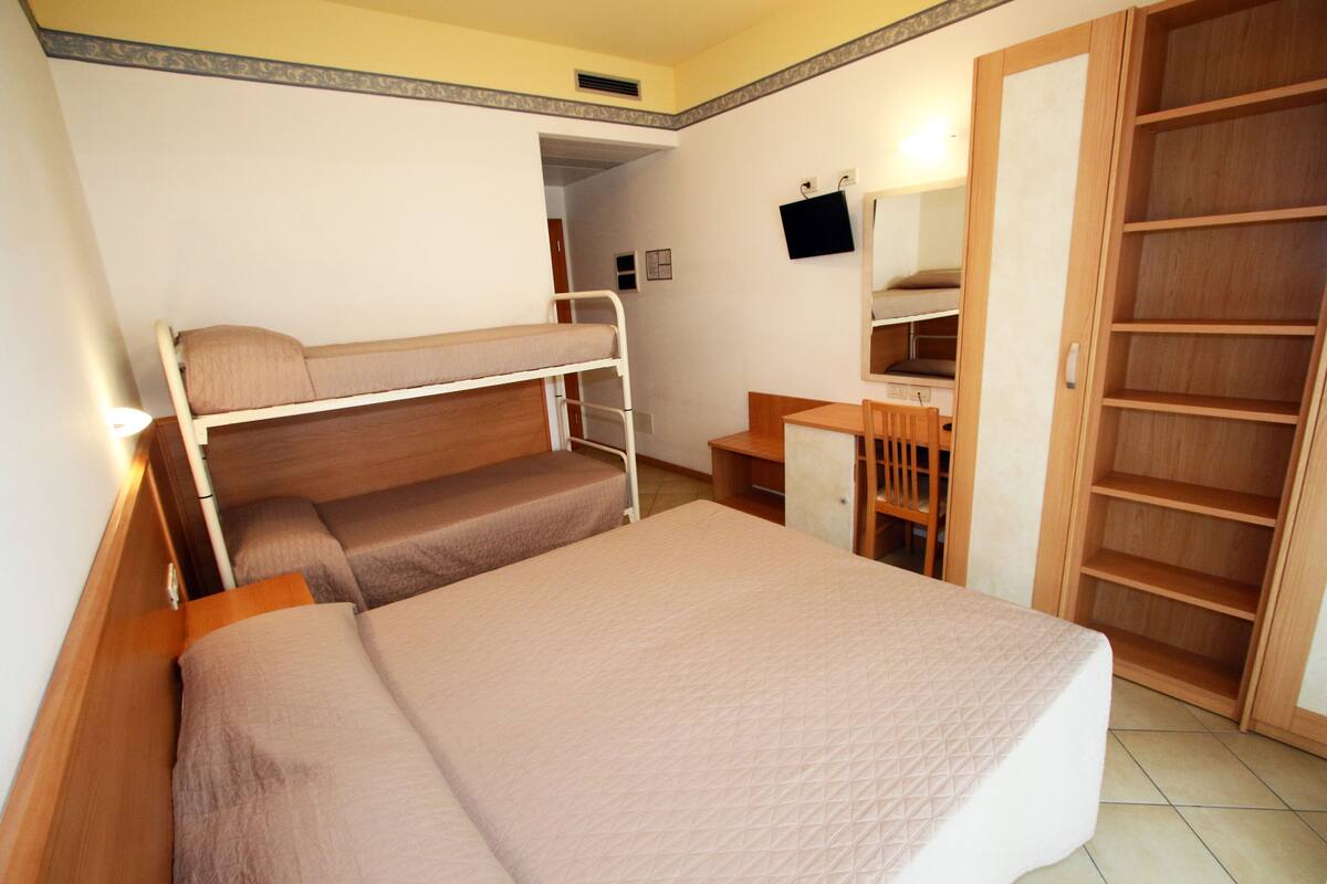 Une chambre avec un lit superposé, un bureau, une chaise et une armoire.