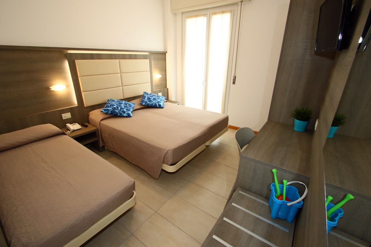 Une chambre d’hôtel avec deux lits, une télévision, un petit bureau et une salle de bain.