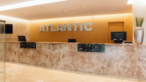 A reception desk with the word "ATLANTIC" prominently displayed, a flat-screen TV, and a potted plant. - Bluesea Salina (Santa Eulalia del Rio)