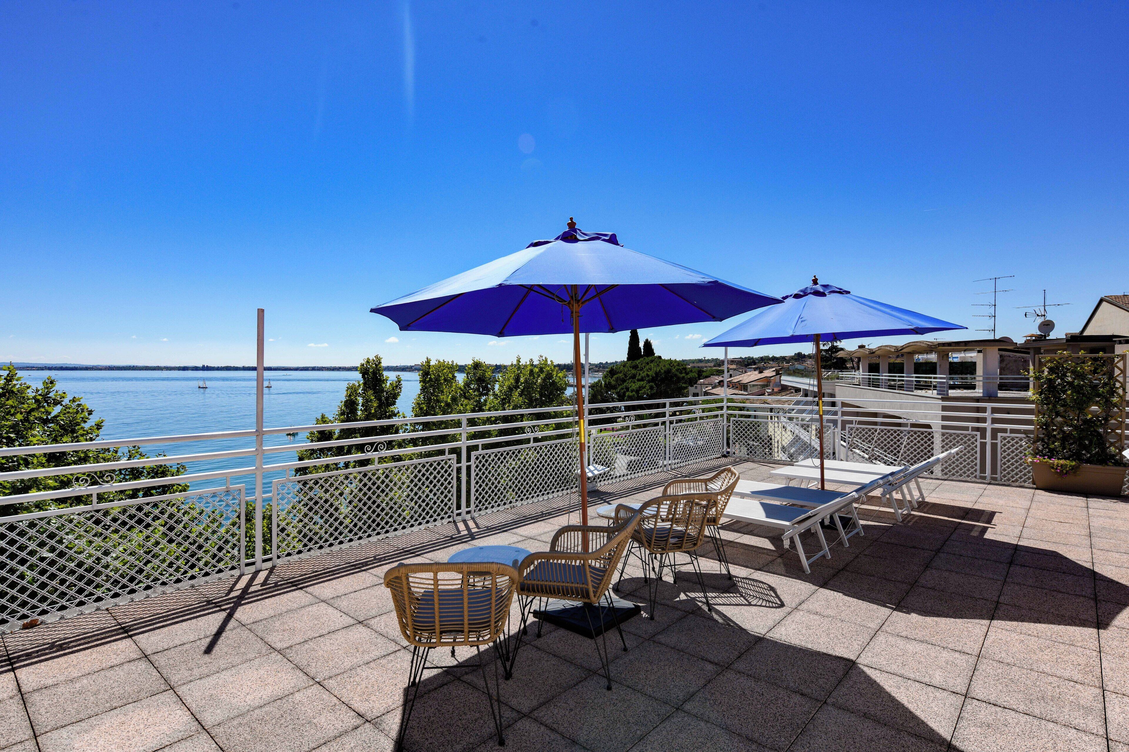 Eine Terrasse mit Sitzgelegenheit, Blick aufs Meer und einer Brüstung.