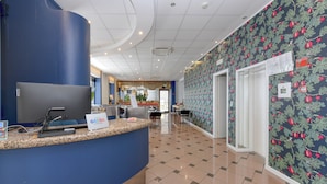 Un'area reception con un bancone blu, un grande schermo e un muro decorato.