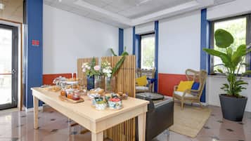 Ein Zimmer mit Esstisch, gedecktem Tisch, Zimmerpflanze und Korbstuhl.