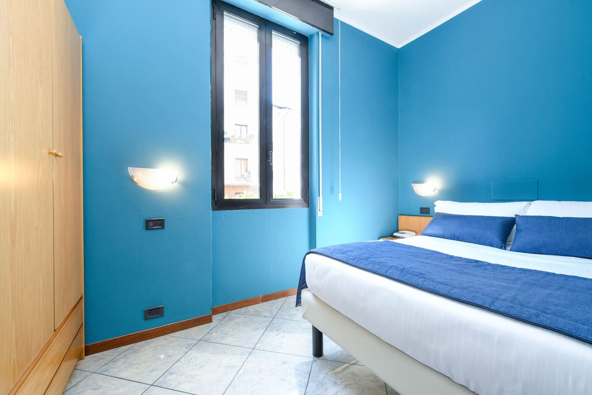 A bedroom with a bed, a window, and a wardrobe.