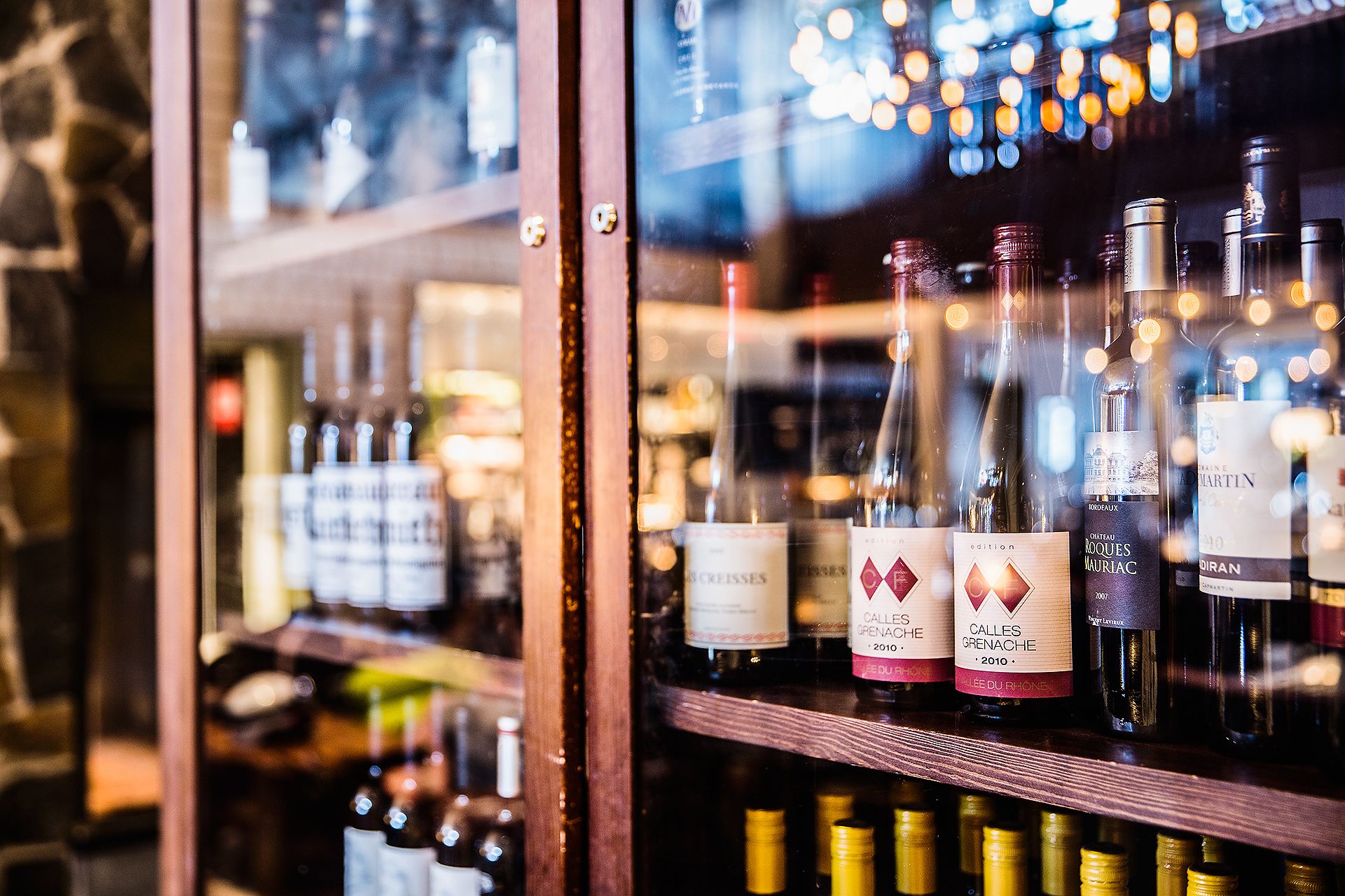 A wine rack with bottles of wine, including Chateau Roques Mauriac and Calès Grenache.